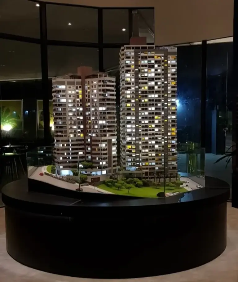 Maquete redonda de empreendimento imobiliário com duas torres residenciais iluminadas